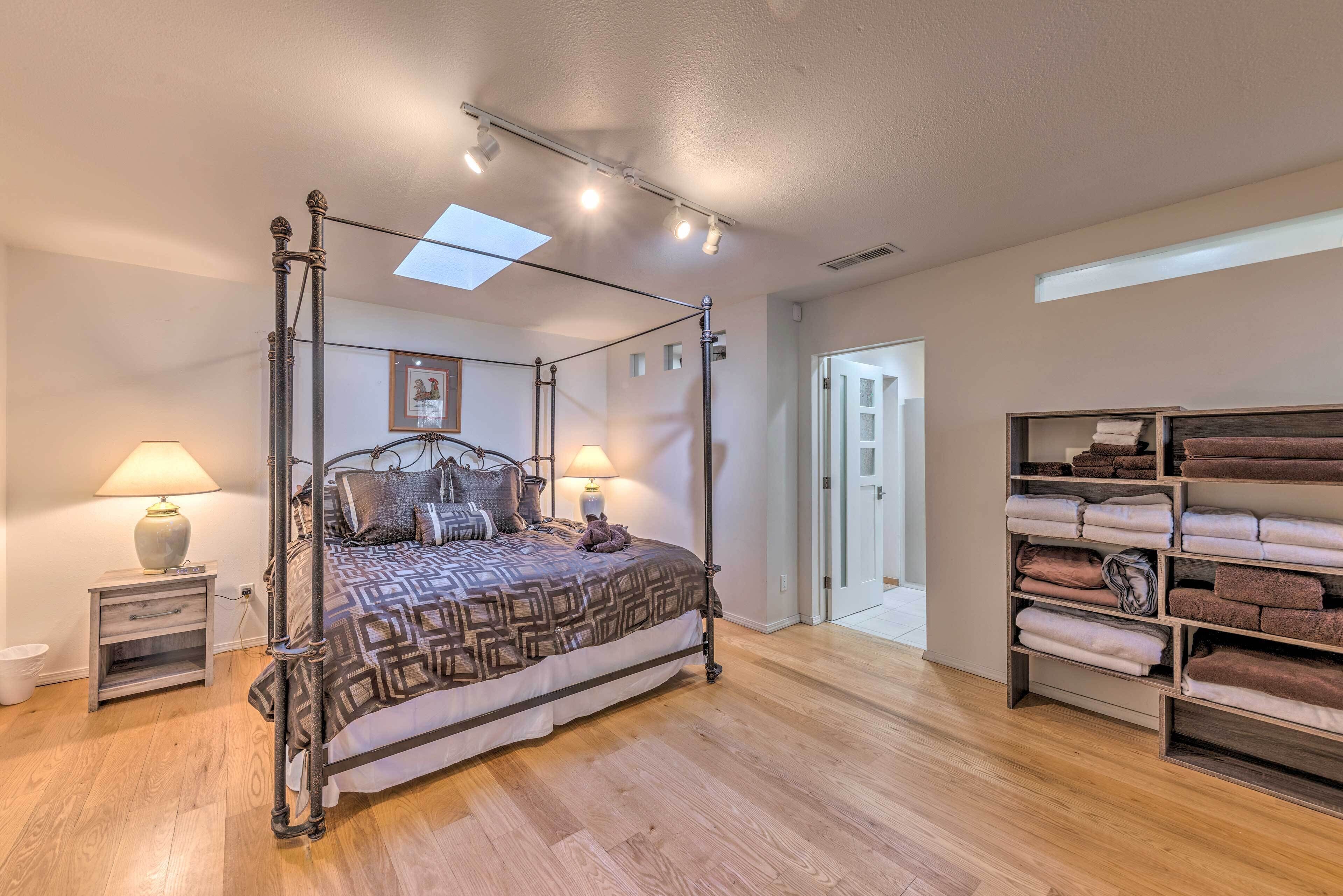 A four-poster bed with a patterned bedspread, bedside lamps, and a wooden floor.