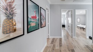 Un couloir aux murs ornés de tableaux encadrés, doté d’un plancher en bois et de portes donnant sur d’autres pièces.