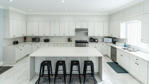 Une cuisine moderne avec des meubles blancs, un îlot central doté de tabourets et des appareils électroménagers intégrés.