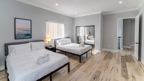 Une chambre d’hôtel moderne avec deux lits, un grand miroir et une vue sur la mer par la fenêtre.