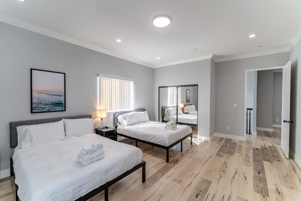 Habitación de hotel moderna con dos camas, un espejo grande y vista al mar por la ventana.