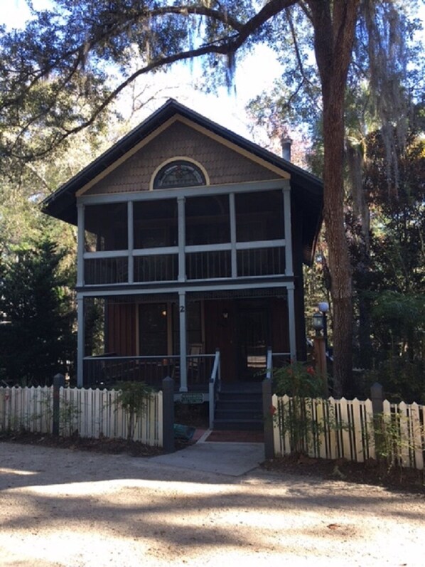 A two-story building with a porch, a small staircase, and a picket fence.