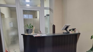 A reception desk with a computer, a welcome sign, and a potted plant.