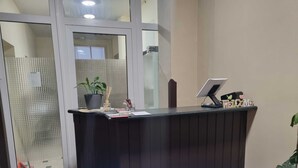 Una taquilla amb un ordinador, un cartell de benvinguda i una planta en test.