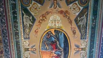 A detailed ceiling fresco with intricate designs and a central oval painting.