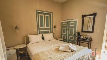 A bedroom with a bed, a small bedside table, a wardrobe, and a mirror on the wall.