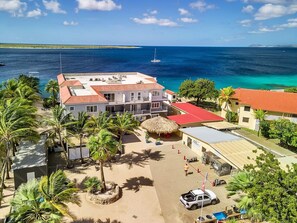 A beachfront property with a large building, a swimming pool, and a view of the ocean.