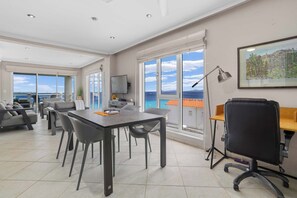 A spacious room with a large table, chairs, a desk with a computer, and a chair with wheels. There is a large window with a view of the ocean and a door leading to another room. - Den Laman Tuna, sea views and beach access (Kralendijk)