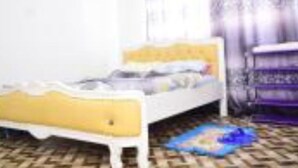 Un letto con una testiera gialla, un comodino e un tappeto decorato sul pavimento.