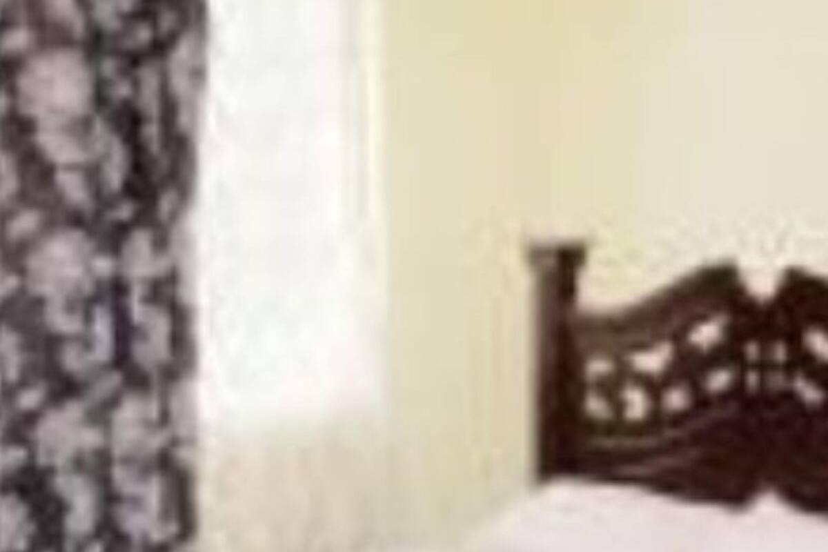 A bedroom with a wooden bed, a patterned curtain, and a window with blinds.