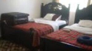 Camera d'albergo con due letti, tappeto decorato e una finestra con tende.