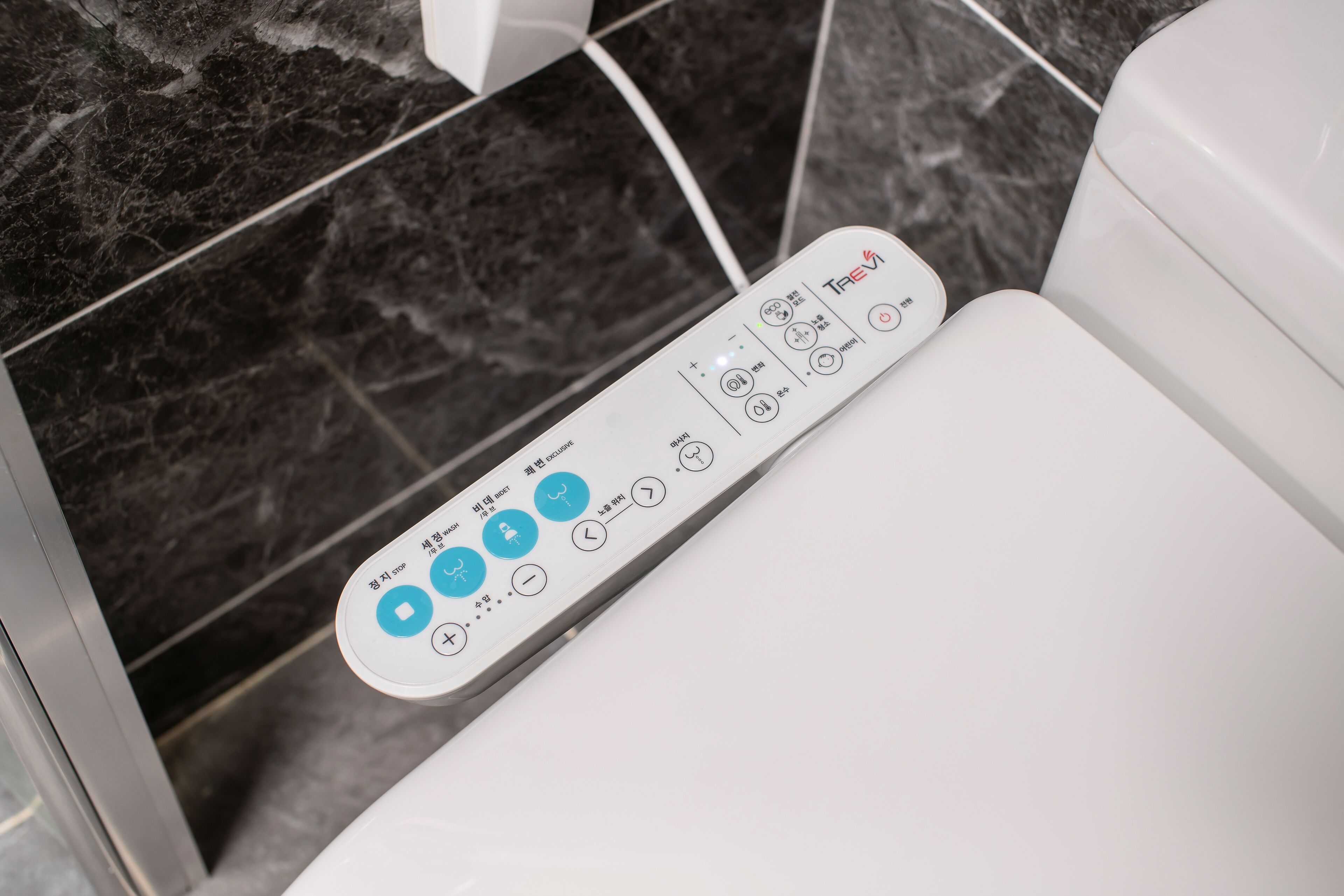 Eine Toilette mit einer Bedienkonsole und Knöpfen für verschiedene Funktionen.