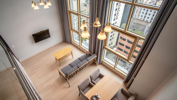Un intérieur moderne avec une table à manger en bois, des sièges confortables et de grandes fenêtres donnant sur la ville.