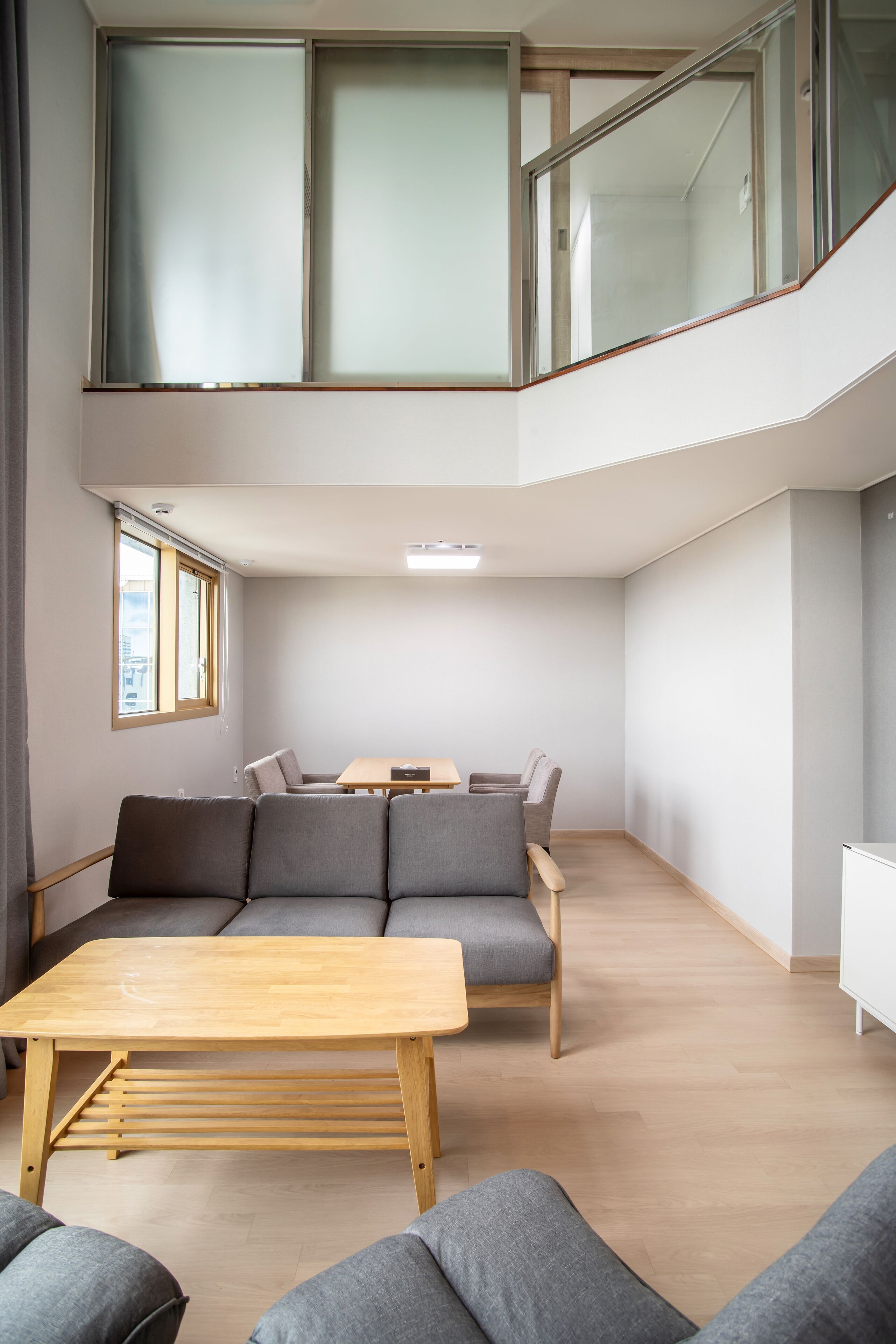 Un espace de vie moderne à plusieurs niveaux, comprenant un coin repas, un ensemble de canapés et un escalier.