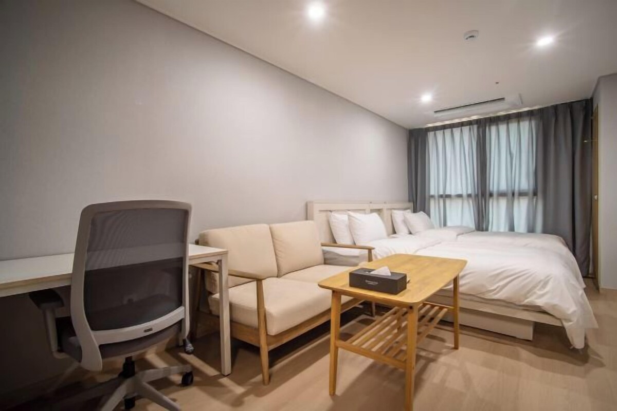 Une chambre d’hôtel moderne équipée d’un lit, d’un bureau, d’une chaise et d’une petite table.