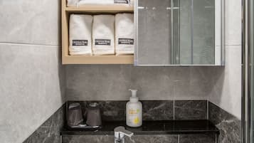Un baño con lavamanos blanco, un espejo y un estante con toallas.