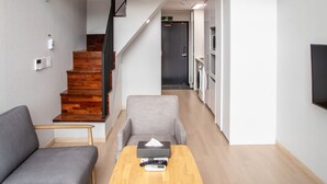 Un appartement moderne doté d’un escalier en bois, d’un canapé, d’une table basse et d’un coin cuisine.