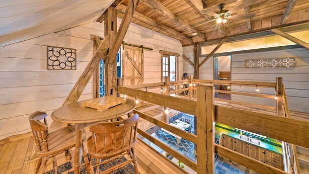 Interior de madera con comedor, ventilador de techo y vista a una piscina al aire libre.
