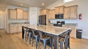 A spacious kitchen with a large island, wooden cabinets, stainless steel appliances, and a fire extinguisher on the wall. - Garden City Retreat w/ Access to Bear Lake! (Garden City)