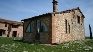 A small stone building with a tiled roof, arched windows, and a chimney. - Charming Tuscan Farmhouse (Arbia Asciano)