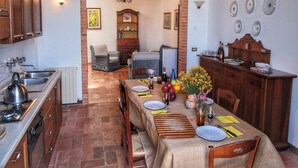 Una cocina acogedora con comedor, que presenta suelo de piedra, armarios de madera y una araña.