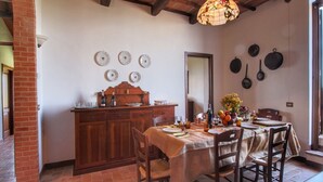 Un comedor con una mesa de madera dispuesta para cuatro, una pared de ladrillo y una lámpara colgante.