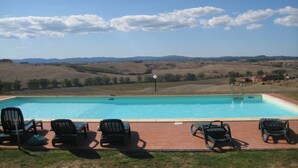 Una piscina con sillones de descanso y vistas a colinas ondulantes.