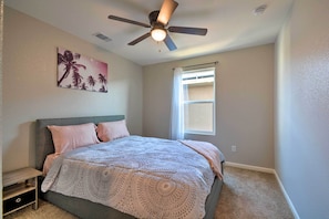 Un dormitorio con una cama, ventilador de techo, ventana y una obra de arte en la pared.