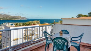 Un balcon avec une table et des chaises donnant sur une vue panoramique de la côte.
