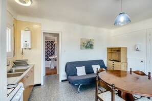 A compact kitchen with a sink, stove, and a dining area with a table and chairs.