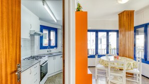 Eine Küche mit weißen Schränken, einem Herd und einem Fenster mit blauem Rahmen.