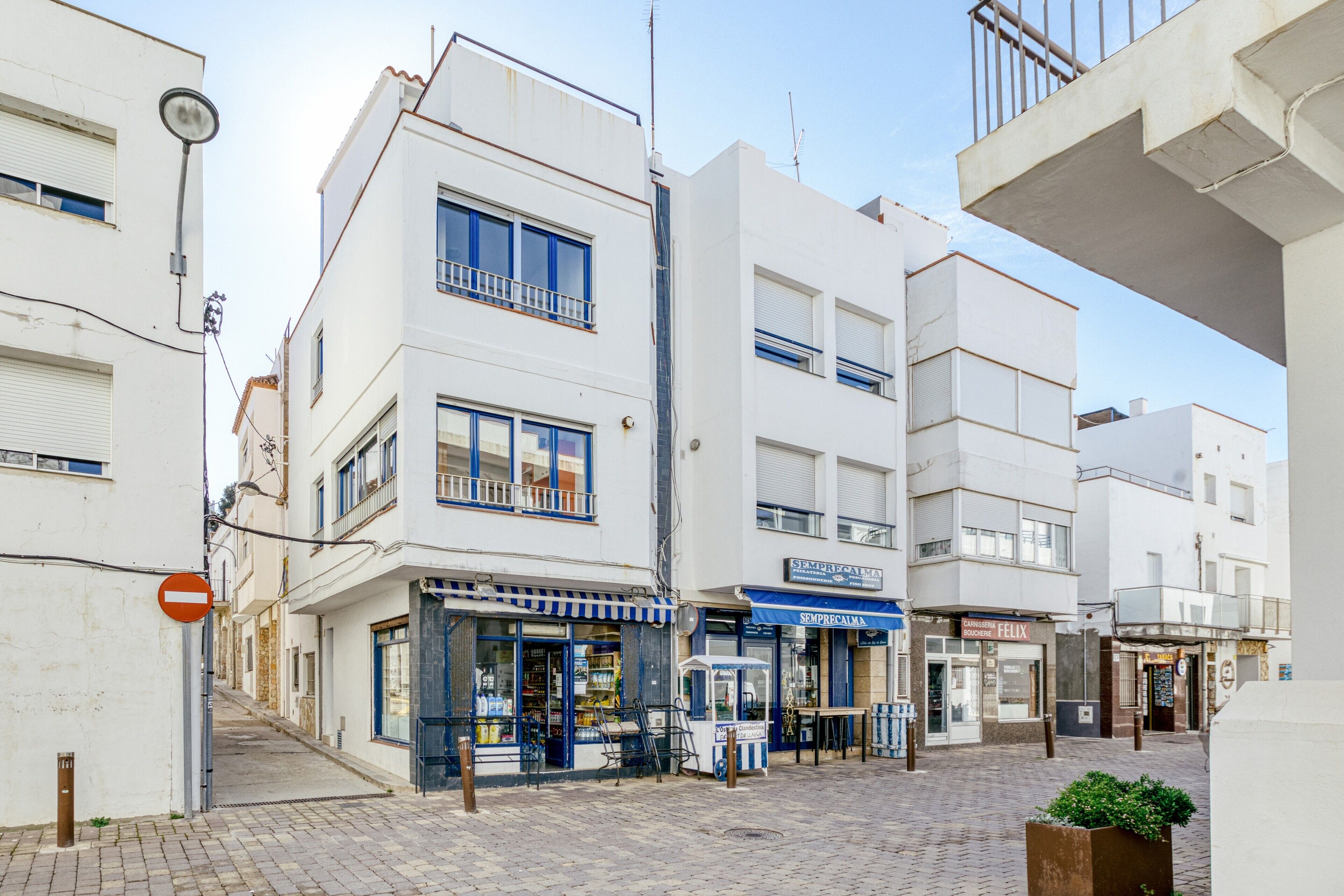 A street with buildings, a no entry sign, and a kiosk.