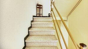 Eine Treppe mit Handlauf und einem Stuhl oben.