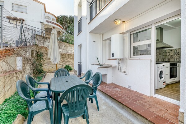 A patio with a table and chairs, a washing machine, and a window with a view of the surrounding area.