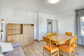 A room with a wooden dining table, chairs, a sofa, and a wardrobe.