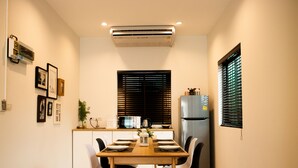 A compact kitchen with a dining table, chairs, a refrigerator, and a window with blinds. - Hua-Hin Private pool villa (Tambon Hin Lek Fai, Amper Hua-Hin)