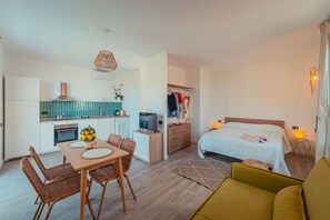 A compact hotel room with a kitchenette, a dining area, and a bed.