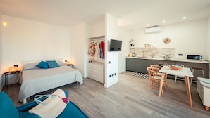 Een moderne hotelkamer met een bed, nachtkastjes, een bureau en een kitchenette.