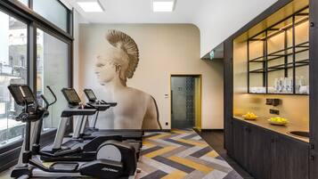 A modern fitness room with treadmills, a wall-mounted sculpture, and a kitchen area with a sink and countertop.
