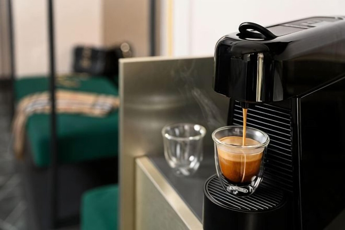 A coffee machine dispensing coffee into a glass cup.