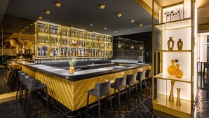 Zona de bar moderna con una barra central, taburetes y una exhibición de botellas.