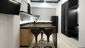 Une cuisine moderne dotée d’un îlot central, de tabourets de bar, d’un téléviseur à écran plat et d’une lucarne.