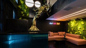 Un espace de détente moderne comprenant un comptoir d’accueil, un canapé et une sculpture d’arbre décorative.