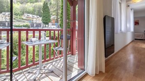 A balcony with a table and chairs, a sliding glass door, and a view of a mountainous area. - Apartment Near Cable Car, Shops & Amenities, East-Facing with Balcony (Cauterets)