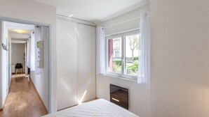 A bedroom with a bed, a window, a wardrobe, and a radiator. - Apartment Near Cable Car, Shops & Amenities, East-Facing with Balcony (Cauterets)