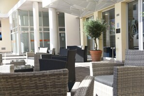 An outdoor seating area with wicker furniture and a potted tree. - Hotel Duca d'Aosta (Mogliano Veneto)