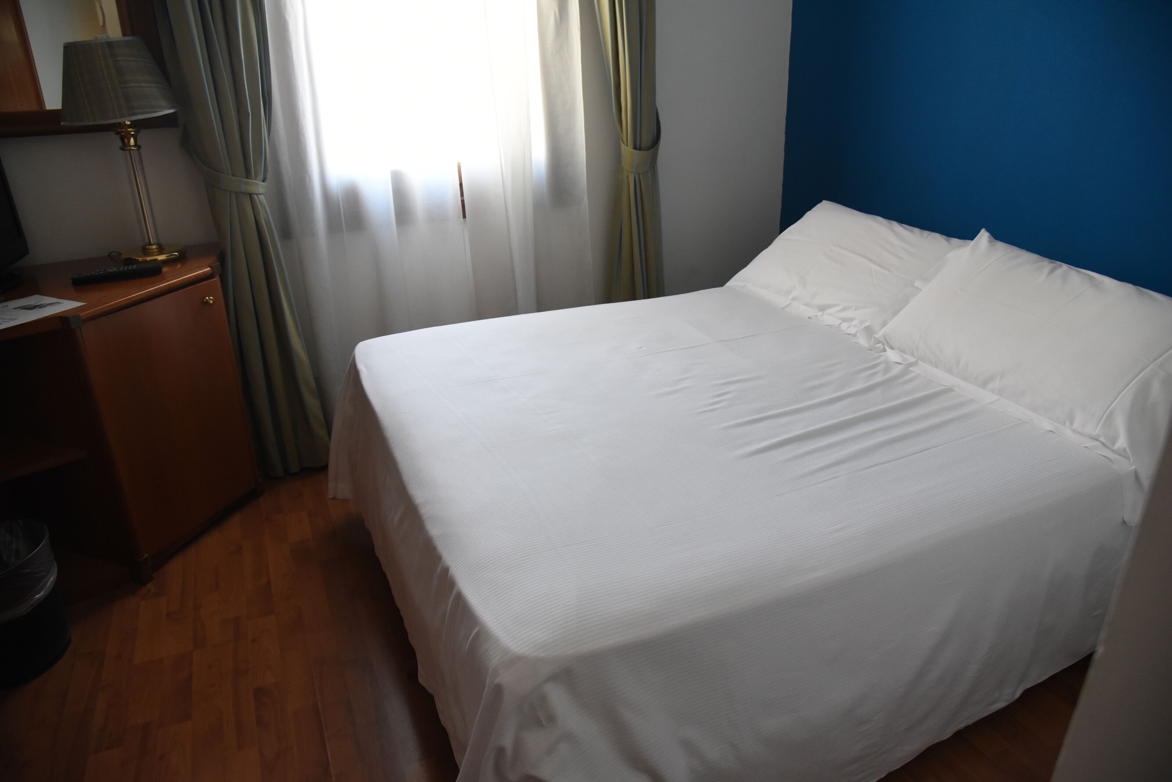 A hotel room with a bed, a desk, and a lamp.