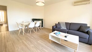 A modern living room with a grey sofa, a white coffee table, and a dining area with a table and chairs. - Ajaccio: Appartement 3 pièces, 6 couchages, 600m de la plage, climatisé, centre-ville (Ajaccio)