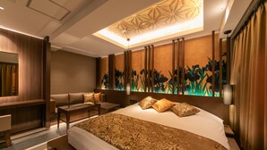Una habitación de hotel moderna con una cama grande, una zona de estar y un muro decorativo.