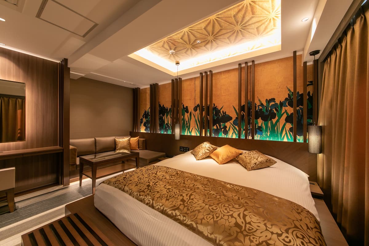 Quarto de hotel moderno com uma cama grande, área de estar e um painel decorativo.